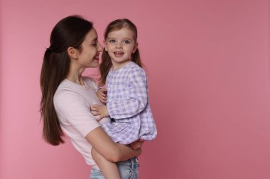 Mutlu bir anne ve pembe arka planda küçük tatlı bir kızı var. Mesaj atmak için yer var.