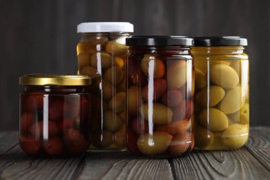 Cam kavanozlarda zeytin turşusu. Ahşap masada, gri arka planda.