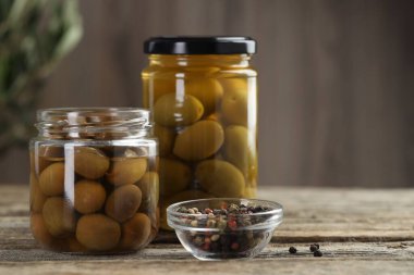 Cam kavanozlarda zeytin turşusu ve ahşap masada baharatlar, yakın plan. Metin için boşluk
