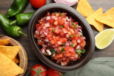 Tabakta nefis salsa, cips ve ahşap masada malzemeler.