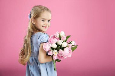 Pembe arka planda bir buket güzel bahar çiçeğiyle sevimli küçük kız, mesaj atmak için yer.