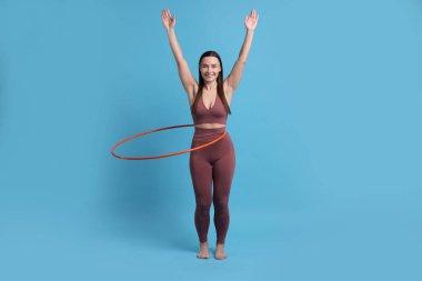 Gülümseyen kadın eğitimi açık mavi arka planda hula hoop ile