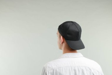 Beyzbol şapkalı, açık gri arka planda, arka planda bir adam. Tasarım için model