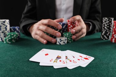 Kumar masasında poker oynayan kart ve kumarhane fişleri olan adam, yakın plan.