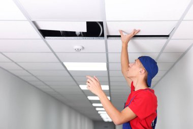 Askıya alınmış tavan kurulumu. Kapalı alanda PVC fayansla çalışan inşaatçı