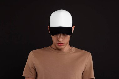 Siyah arka planda şık beyzbol şapkalı bir adam. Tasarım için model