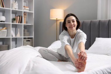 Evde yatakta egzersiz yapan genç bir kadın. Sabah rutini