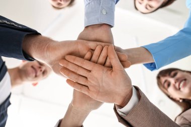Takım çalışması. Bir grup insan kapalı alanda el ele tutuşuyor.