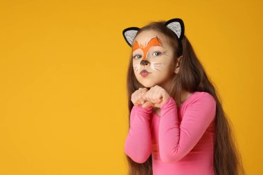 Turuncu arka planda kedi gibi boyalı yüzü ve kulakları olan tatlı bir kız.