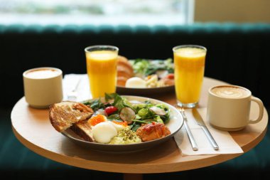 Lezzetli bir kahvaltı. Kafedeki ahşap masada farklı yemekler ve içecekler servis ediliyor.