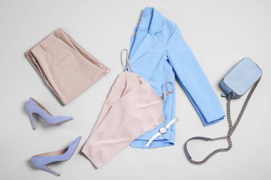 Açık gri arka planda şık kıyafetler, topuklu ayakkabılar ve aksesuarlar, düz yatış