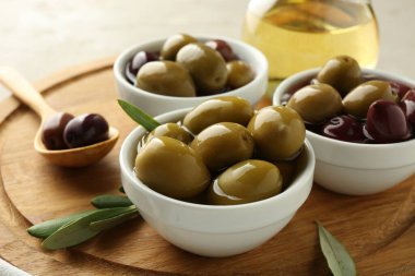 Lezzetli marine edilmiş zeytinler kaseler, kaşık, yağ ve yeşil yapraklar masada, yakın çekim