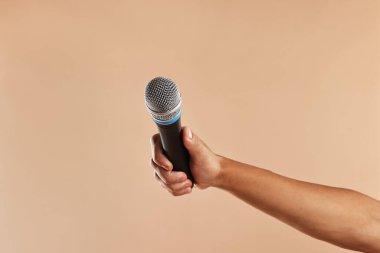 Bej arka planda mikrofonu olan adam, yakın plan.