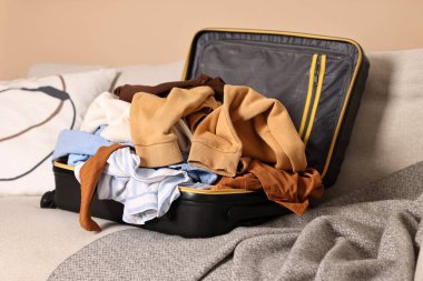 İçerideki kanepede farklı kıyafetlerle dolu bir bavul aç.