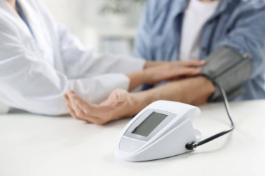 Hastanedeki randevu sırasında yaşlı adamın kan basıncını ölçen doktor, yakın plan.