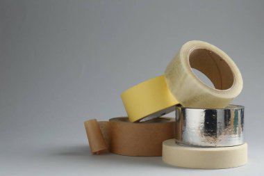 Gri arkaplanda farklı yapıştırıcı bantların ruloları, metin için boşluk