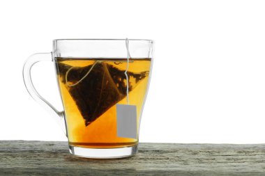 Cam bardakta çay poşeti, beyaz arka planda, ahşap masada sıcak içecek. Metin için boşluk