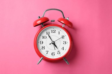 Pembe zemin üzerinde kırmızı alarm saati, üst görünüm