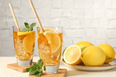 Buzlu çayı pipetle tazelemek, nane ve limon yeşil arka planda hafif desenli masada, yakın plan