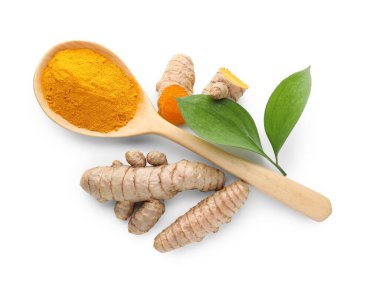 Kaşığın içindeki zerdeçal tozu, beyaz üzerine izole edilmiş yeşil yapraklar ve kökler, üst manzara