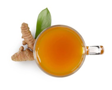 Cam fincanda Aromatik zerdeçal çayı, beyaz üzerine izole edilmiş kökler ve yeşil yaprak, üst manzara
