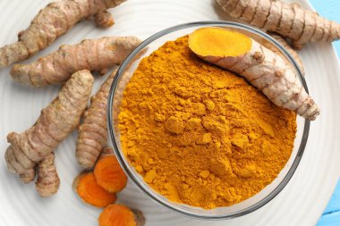 Kasede Aromatik zerdeçal tozu ve açık mavi masada taze kökler.