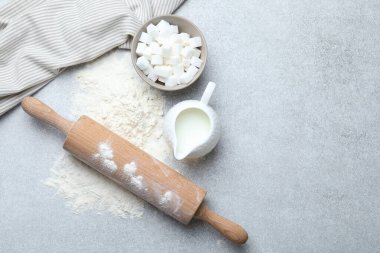 Yuvarlanan iğne, un, şeker küpleri ve açık gri masada süt, düz yatak. Metin için boşluk