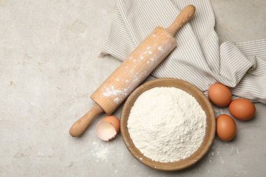 Yuvarlanan iğne, un ve yumurta açık gri arka planda, düz yerde. Metin için boşluk