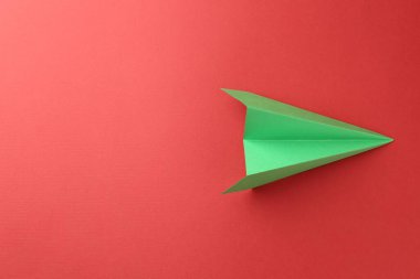 Kırmızı arka planda el yapımı yeşil kağıt uçak, üst manzara. Metin için boşluk