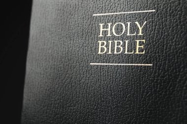 Hardcover Holy Bible in English language on black background, closeup clipart