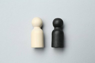 Black and white human figures on light background, flat lay. Racism concept clipart