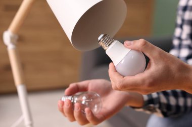 Evdeki lambadaki floresan lambası için parlak ampulü değiştiren adam, yakın plan.