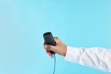 Açık mavi arka planda mikrofonu olan adam, yakın plan.