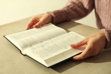 Bej masada İngilizce İncil okuyan kadın, yakın plan.