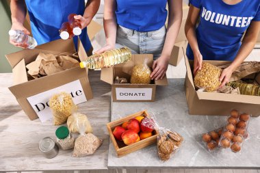 Gönüllüler yemek bağışlarını kapalı masalarda paketliyor.