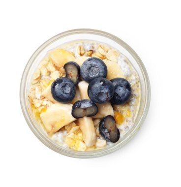 Yaban mersinli lezzetli chia pudingi, muz ve yulaf ezmesi beyaz bardakta izole edilmiş, üst manzara