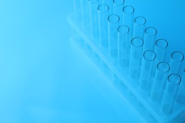 Açık mavi arkaplanda boş test tüpleri, metin için boşluk. Laboratuvar camları.