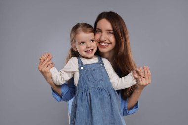 Mutlu anne portresi ve gri arka planda küçük tatlı kızı.