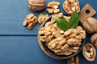 Taze ceviz ve yeşil yapraklar mavi ahşap masada, düz yerde. Metin için boşluk