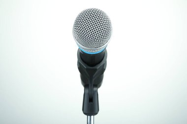 Beyaz arka planda mikrofonla durun, yakın plan. Müzik ekipmanları