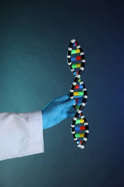 Koyu mavi arka planda DNA yapısına sahip bilim adamı, yakın plan