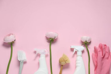 Bahar temizliği. Deterjanlar, malzemeler ve pembe arka planda çiçekler. Metin için boşluk