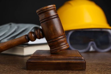 İşte bir kaza oldu. Gavel, güvenlik ekipmanları ve ahşap masadaki kitaplar, seçici odaklanma