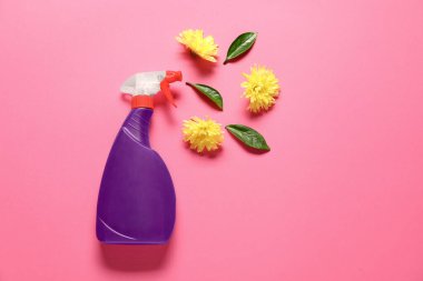 Pembe arka planda bir şişe temizlik malzemesi ve çiçekler, düz konum. Metin için boşluk