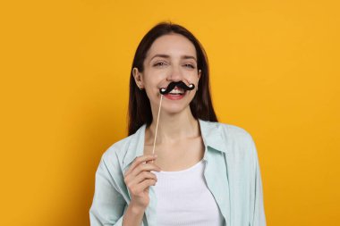 Turuncu arka planda sahte kağıt bıyıklı mutlu kadın.