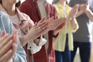 İnsanlar toplantı sırasında alkış tutuyor, yakın çekim görüntüsü.