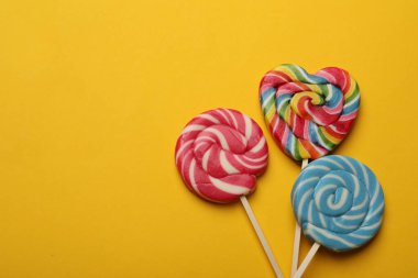 Sarı arka planda leziz lolipoplar, düz yatış. Metin için boşluk