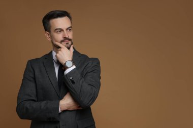 Kahverengi arka planda klasik takım elbiseli yakışıklı bir adam. Metin için boşluk