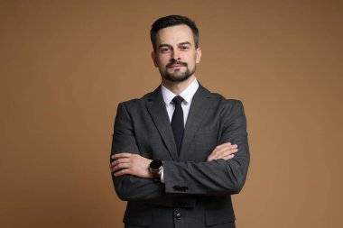 Kahverengi arka planda klasik takım elbiseli yakışıklı bir adam.