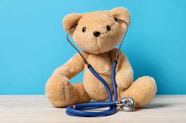 Pediatri konsepti. Masada steteskoplu oyuncak ayı açık mavi arka planda